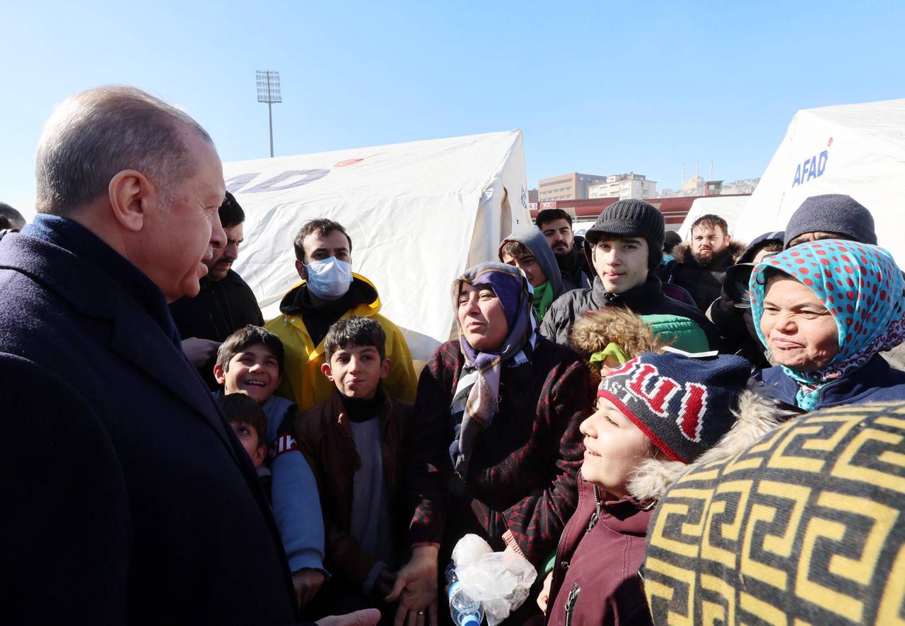 Der türkische Präsident Recep Tayyip Erdogan steht am 8.2.2023 zwischen den vom Erdbeben besonders stark betroffenen Anwohnern der türkischen Provinz 