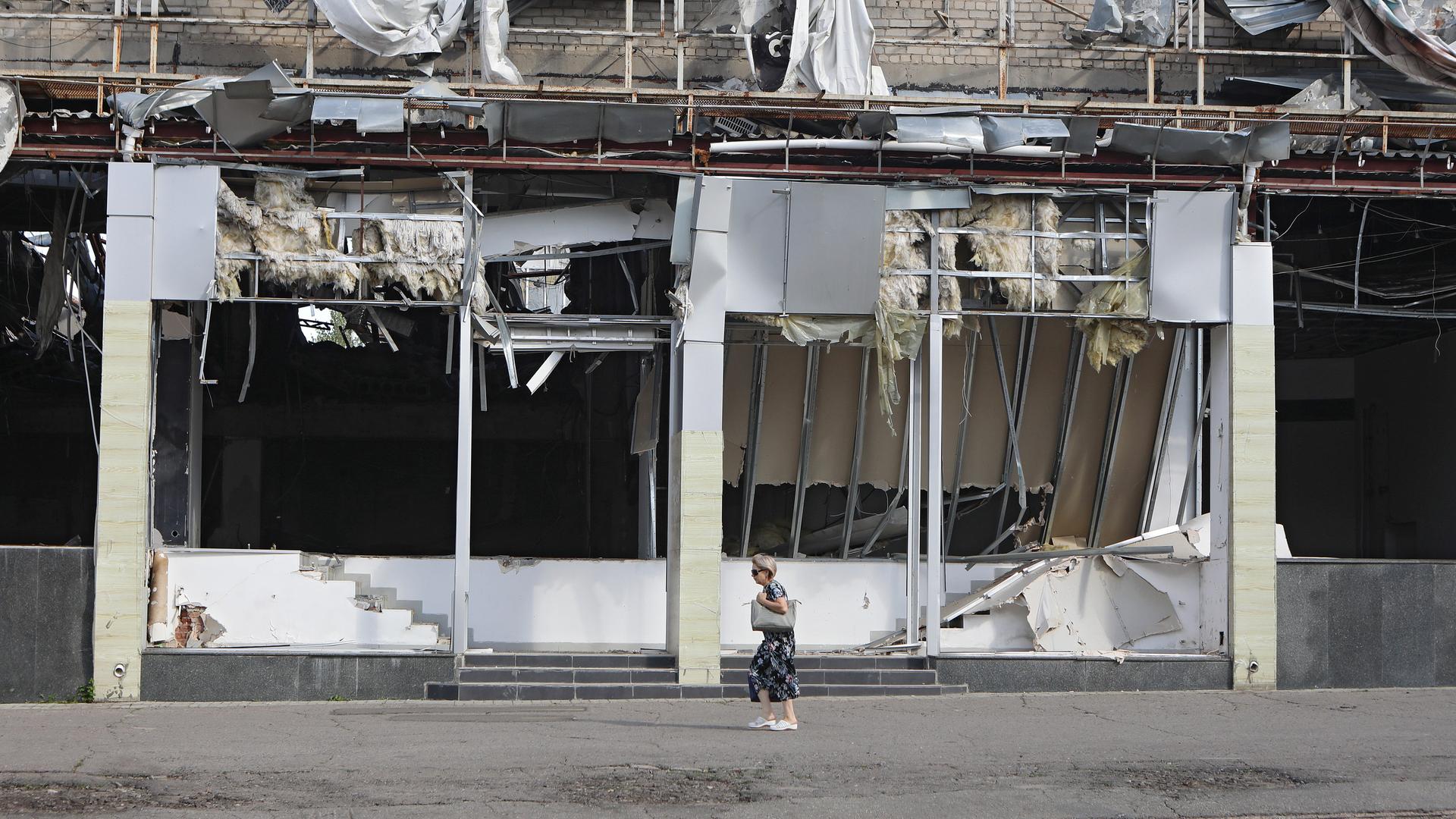 Ukraine, Kramatorsk: Eine Frau geht an einem durch russischen Beschuss zerstörten Gebäude nahe der Frontlinie in der Ostukraine vorbei (Archivbild vom 12.8.24)