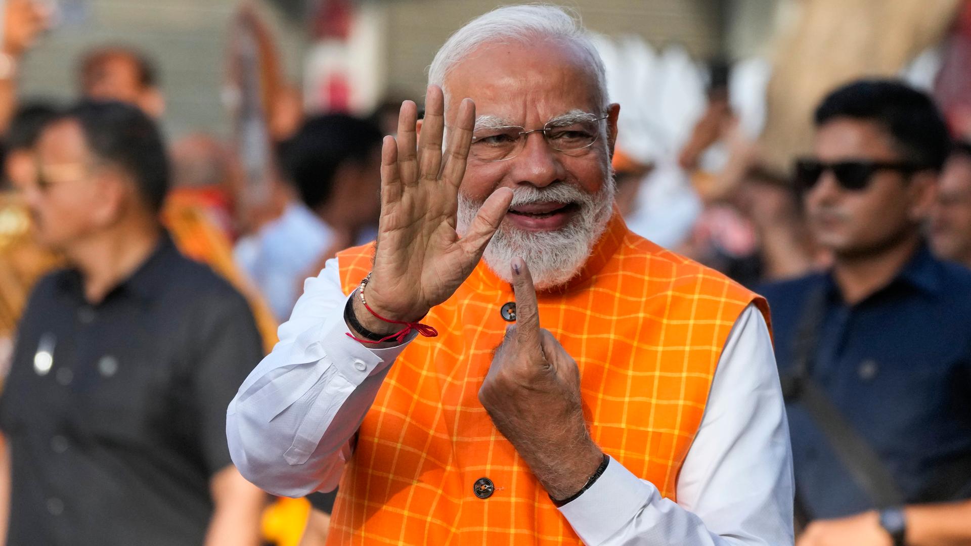 Indien, Ahmedabad: Der indische Premierminister Narendra Modi zeigt den unauslöschlichen Tintenfleck auf seinem Zeigefinger, nachdem er in der dritten Phase der Parlamentswahlen seine Stimme abgegeben hat. 