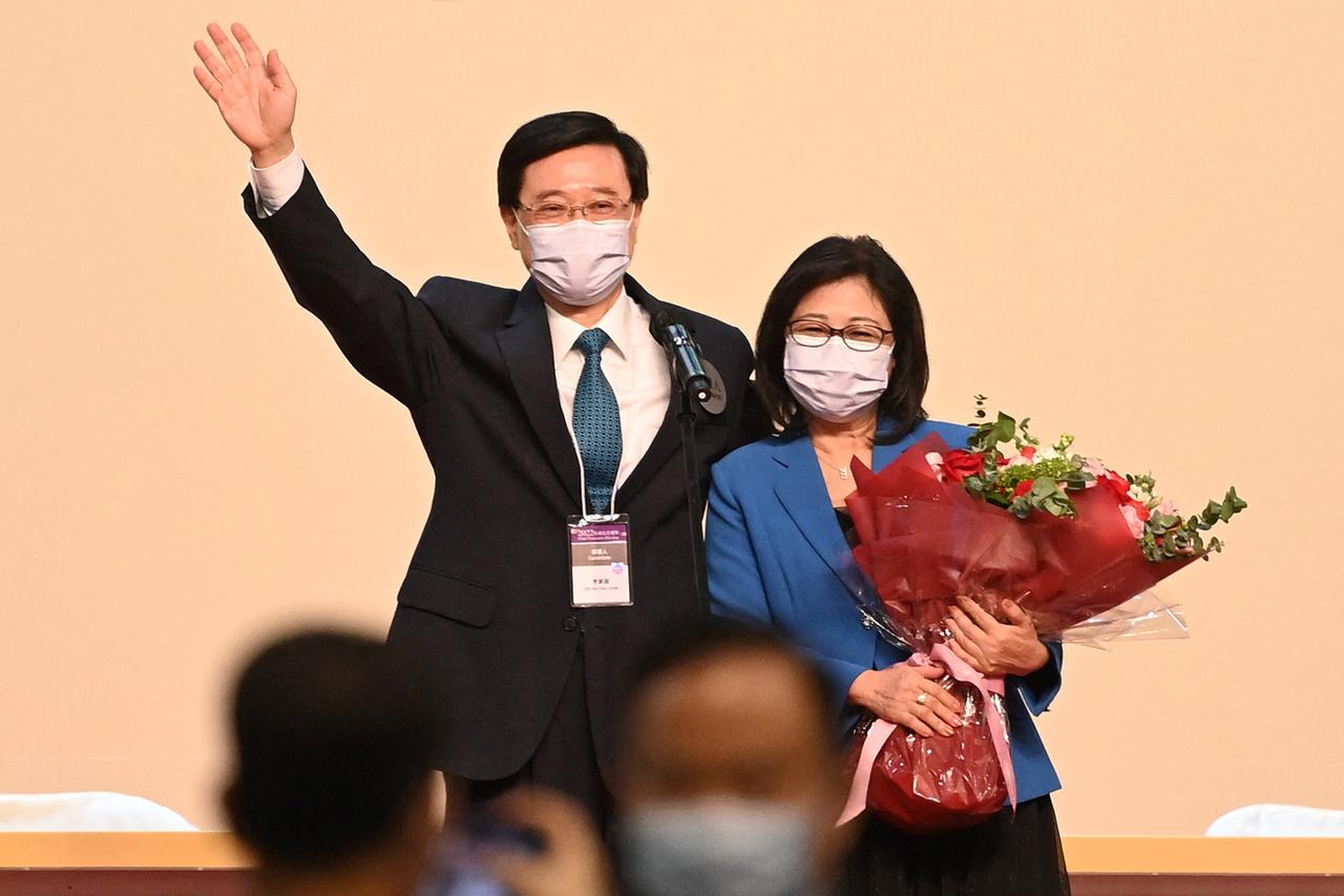 Hongkongs neuer Regierungschef John Lee und seine Frau Janet lächeln und winken.