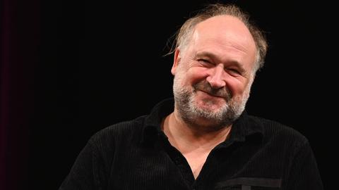 Der Autor Jörg Bong auf der Bühne der Lit Cologne spezial, dem internationale Literaturfestival mit schwarzem Hemd vor schwarzem Hintergrund.