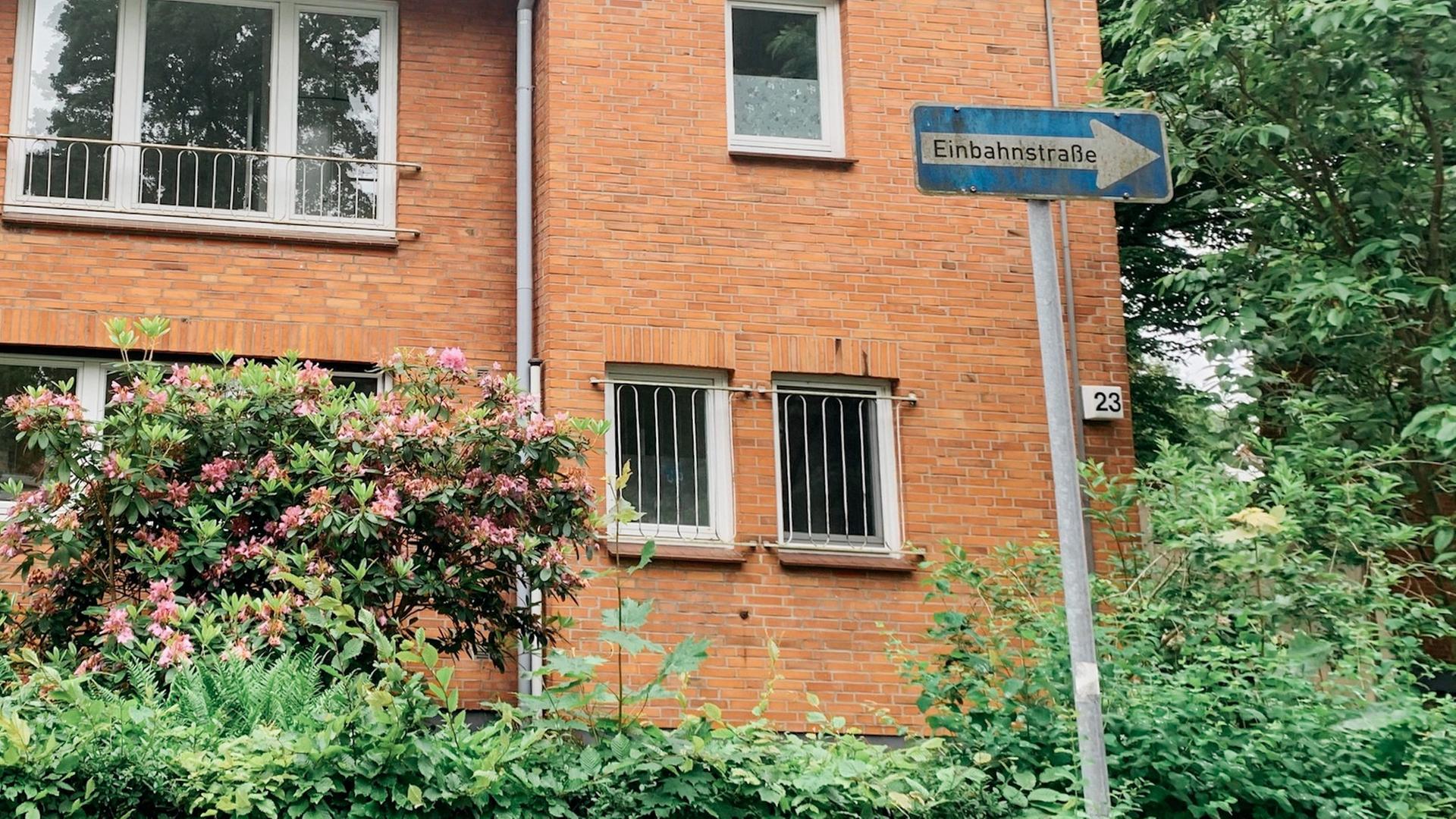 Ein zweistöckiger Klinkerbau in Hamburg im Grotefendweg 23. Im Vorgarten blüht ein Strauch. 
