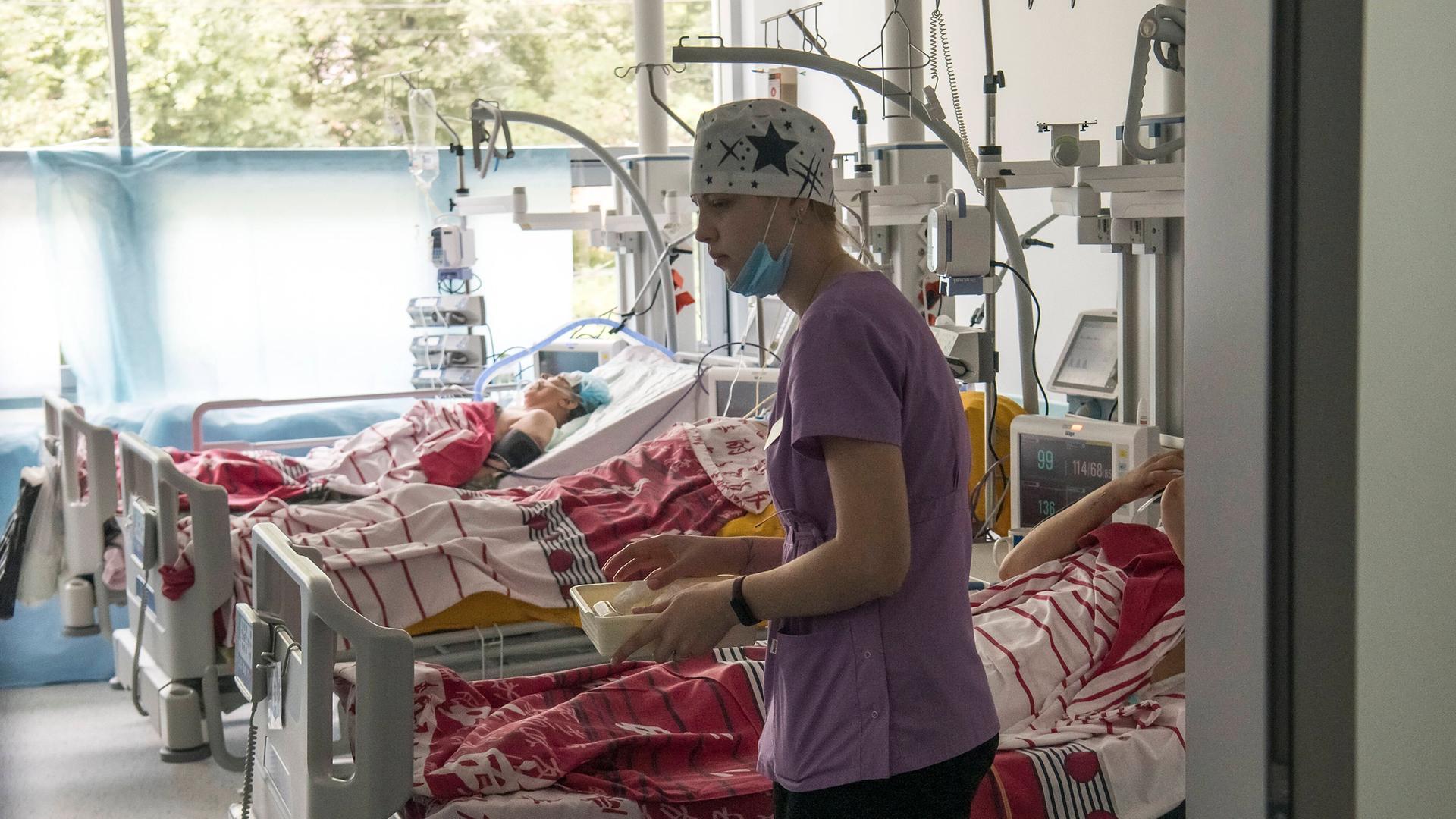 Ein Pfleger bewegt sich vor Betten mit Verletzten in einem Krankenhaus Ein Pfleger bewegt sich vor Betten mit Verletzten in einem Krankenhaus