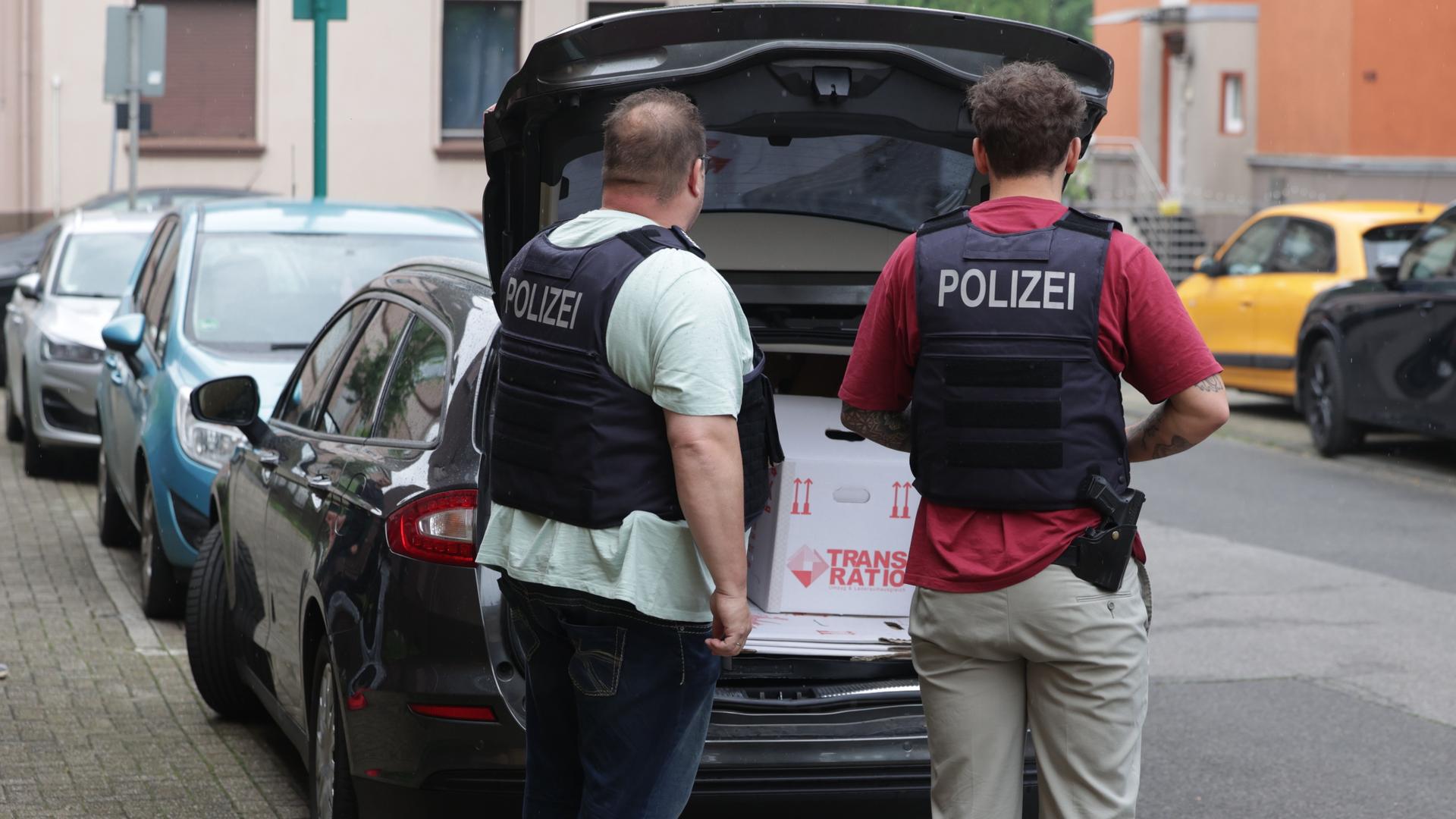 Nordrhein-Westfalen, Duisburg: Nach einer Wohnungs-Durchsuchung verladen Polizisten einen Karton mit sichergestellte Gegenstände in einem Wagen. Nordrhein-Westfalen, Duisburg: Nach einer Wohnungs-Durchsuchung verladen Polizisten einen Karton mit sichergestellte Gegenstände in einem Wagen.
