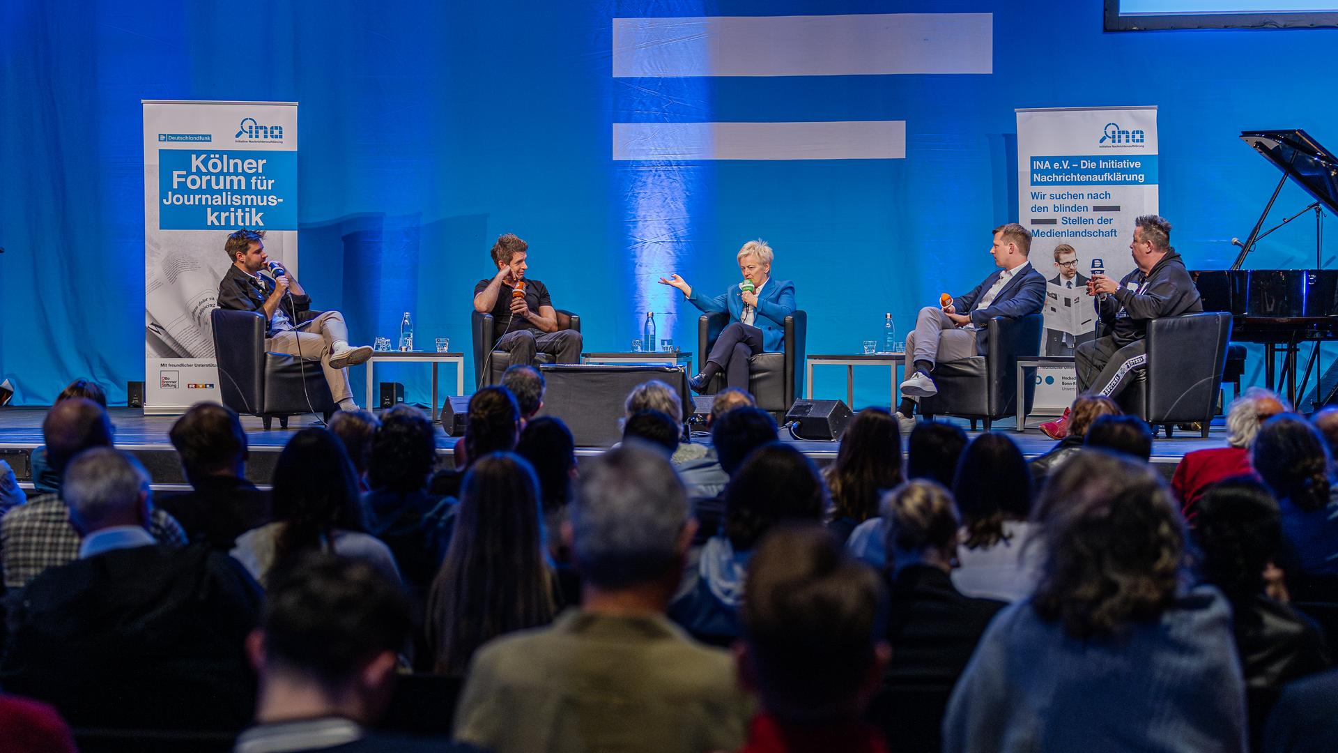 Eine Podiumsdiskussion mit fünf Teilnehmern, die diskutieren.