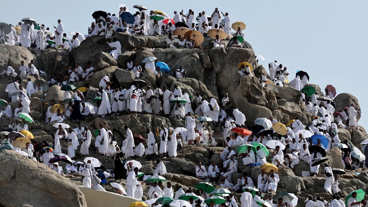 Menschen in weiße Gewänder erklimmen einen Berg in Saudi-Arabien.