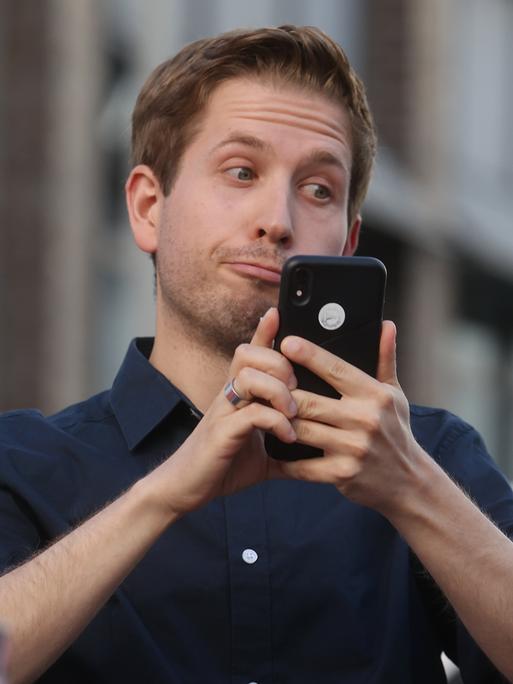 Kevin Kühnert (SPD) schaut auf sein Handy und verdreht die Augen.