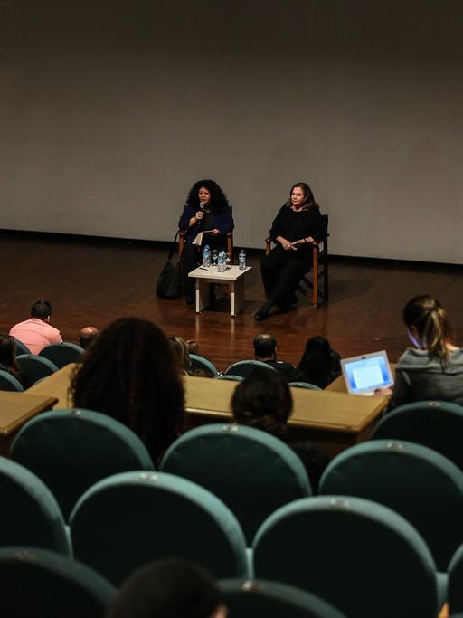 Die Schauspielerin Kathleen Turner sitz hinter einem Tischchen mit Wasserflaschen beim Antalya Filmfestival auf der Bühne. Links neben ihr eine Moderatorin mit Mikrofon.