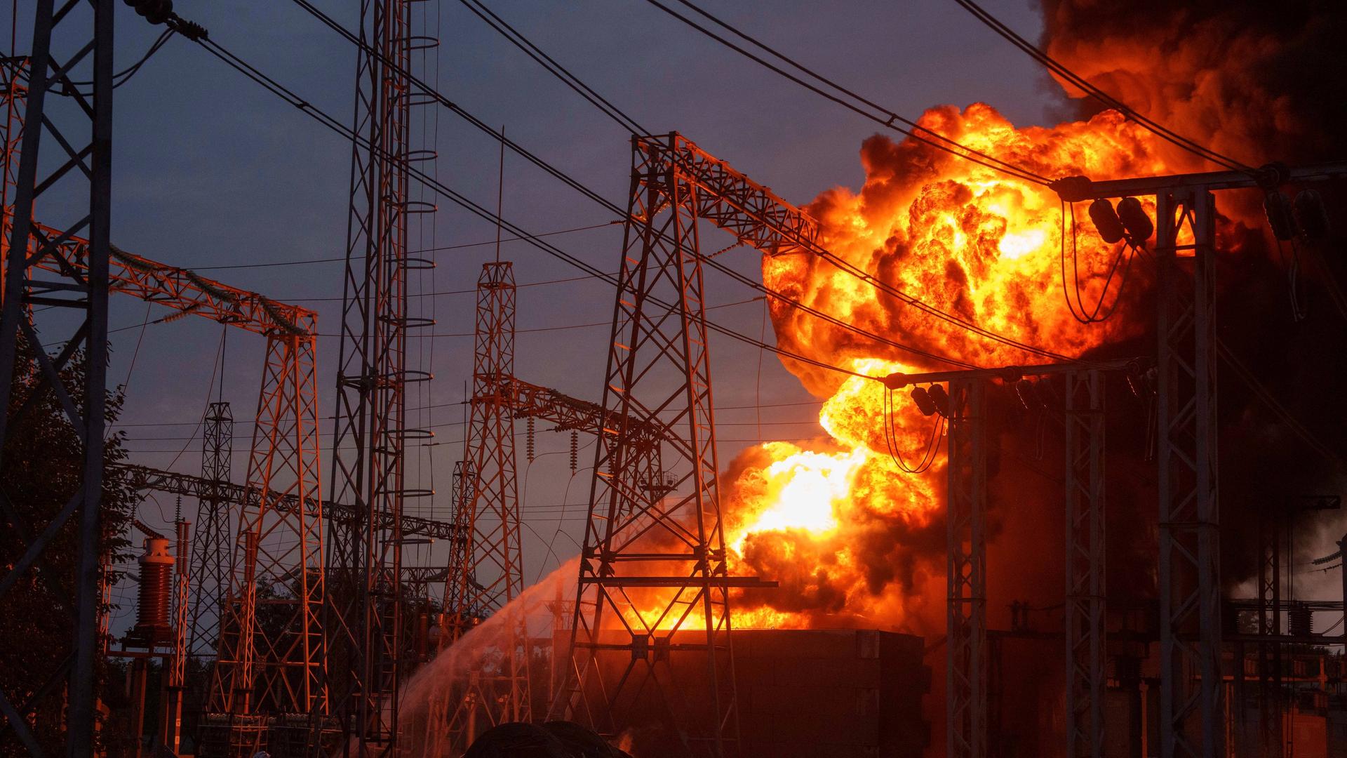Es ist dunkel. Aus den Umrissen einer Elektrizitätsanlage steigt ein Feuerball auf. Es ist dunkel. Aus den Umrissen einer Elektrizitätsanlage steigt ein Feuerball auf.