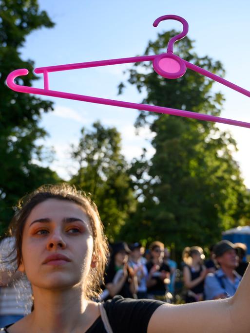 Eine Frau hält bei einer Demonstration in Warschau einen pinken Bügel hoch. Er steht für das Recht auf Abtreibung.