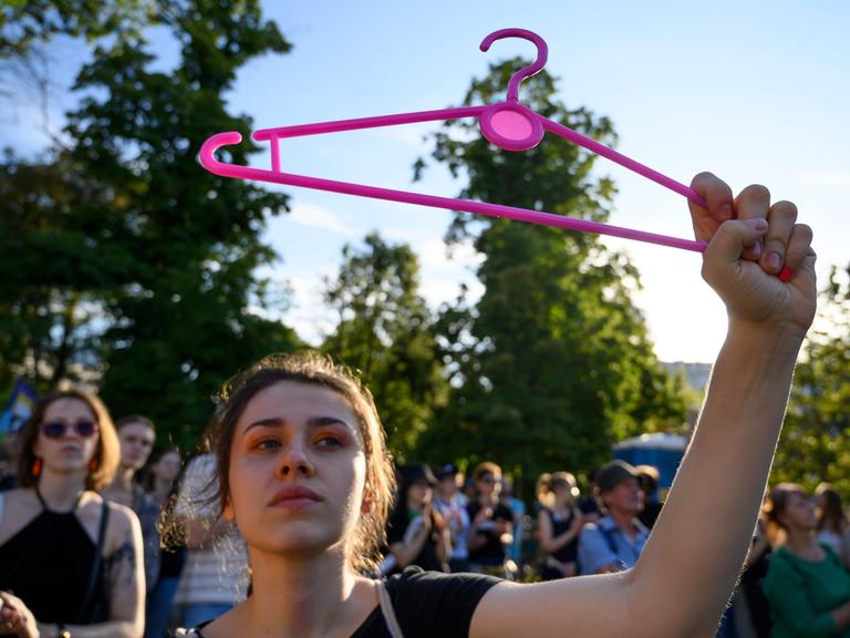 Eine Frau hält bei einer Demonstration in Warschau einen pinken Bügel hoch. Er steht für das Recht auf Abtreibung.