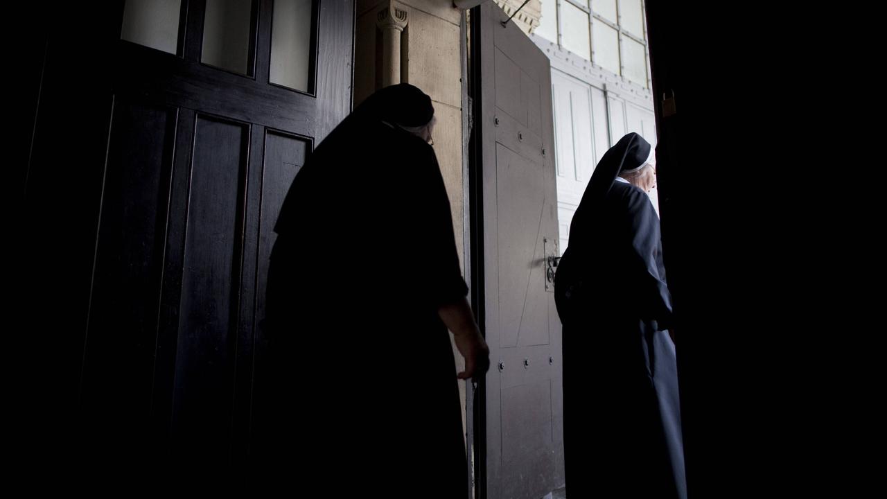 Zwei Ordensfrauen in dunklen Gewändern gehen durch eine Tür.