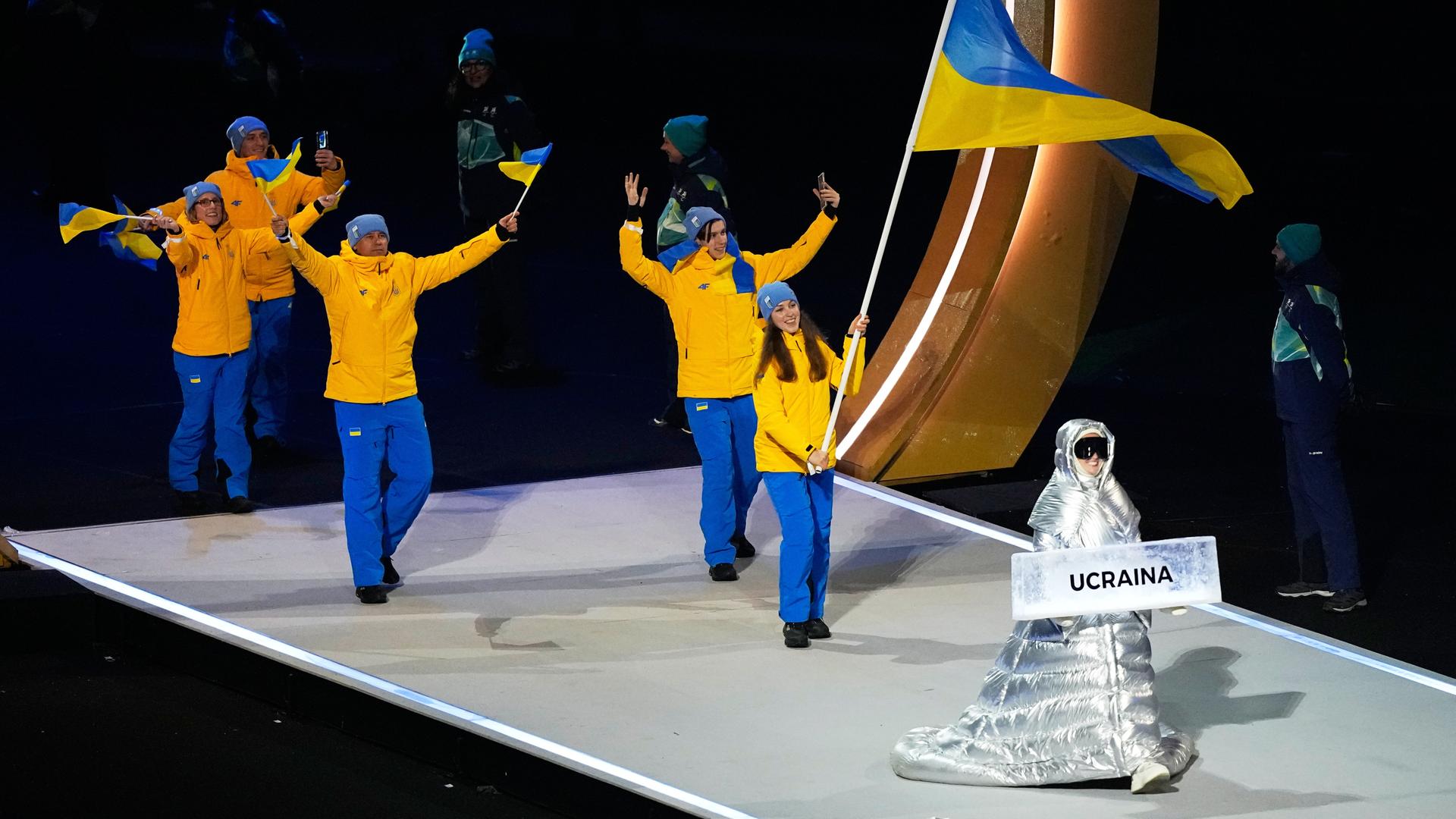 Anastasia Kutscherowa trägt das Schild, als sie die Athleten aus der Ukraine bei der Eröffnungsfeier der Olympischen Winterspiele in die Arena führt.
