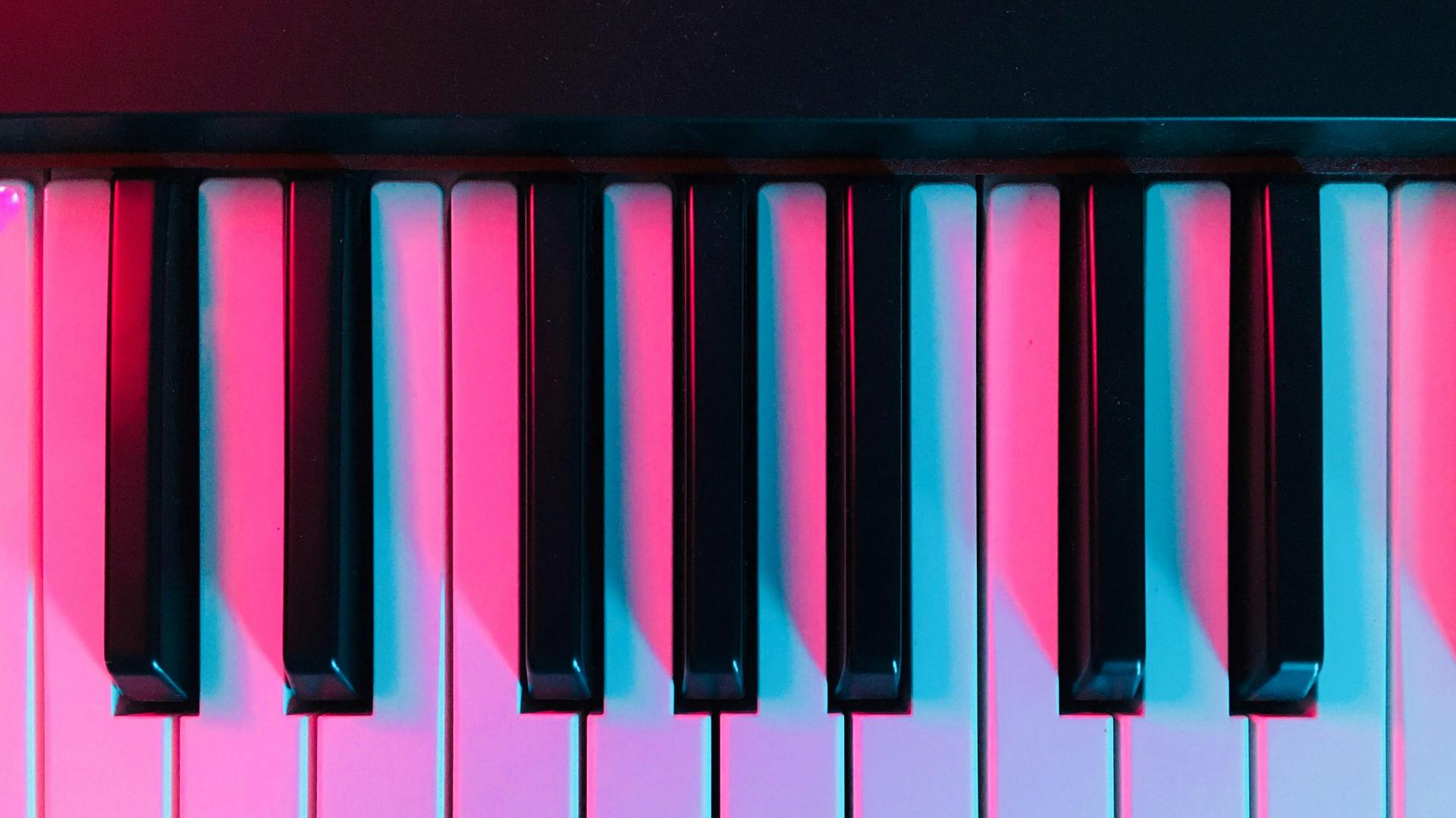 Blick auf moderne Klaviertasten, die in pinkfarbenes Licht getaucht sind.