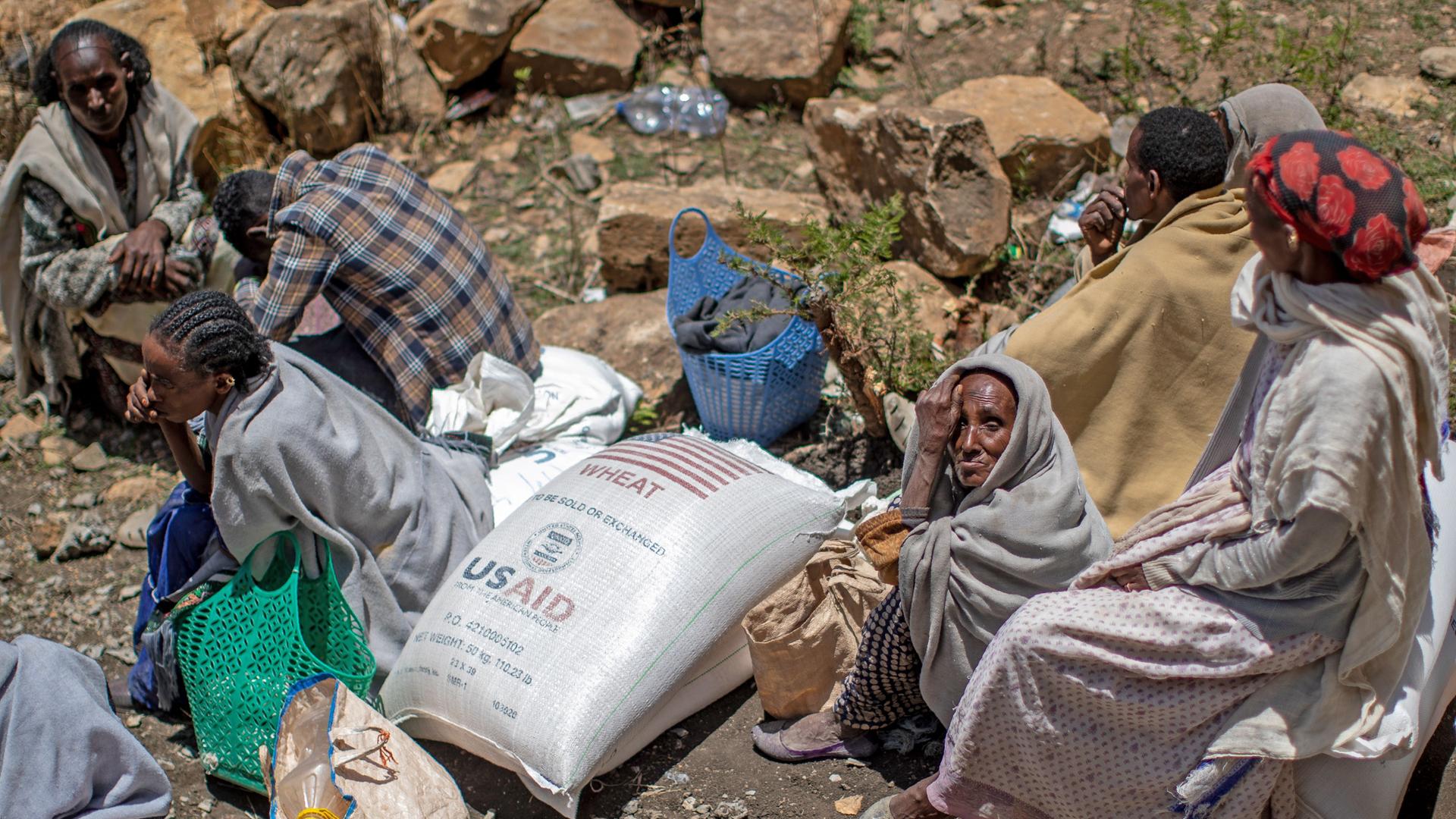 Äthiopien, Agula: Mehrere Menschen sitzen neben einem Sack mit Weizen, nachdem dieser von der Relief Society of Tigray in der Region Tigray im Norden Äthiopiens verteilt wurde.