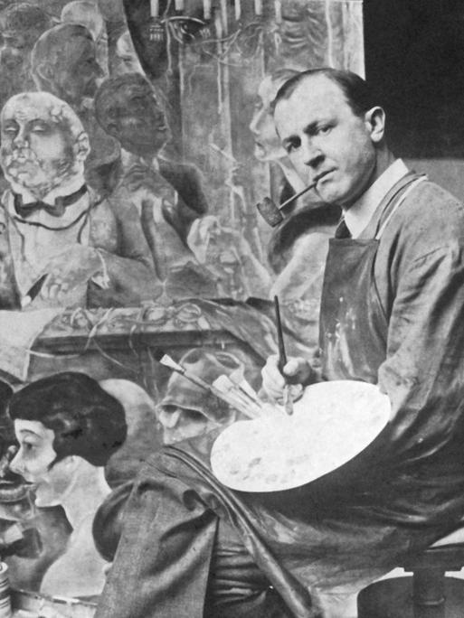 Der deutsche Künstler George Grosz (1893 - 1959) in seinem Atelier vor einem Gemälde. Er war ein prominentes Mitglied der Berliner Dada-Gruppe und der Neuen Sachlichkeit, bekannt vor allem für seine bissigen Karikaturen des Berliner Lebens in den 1920er Jahren.