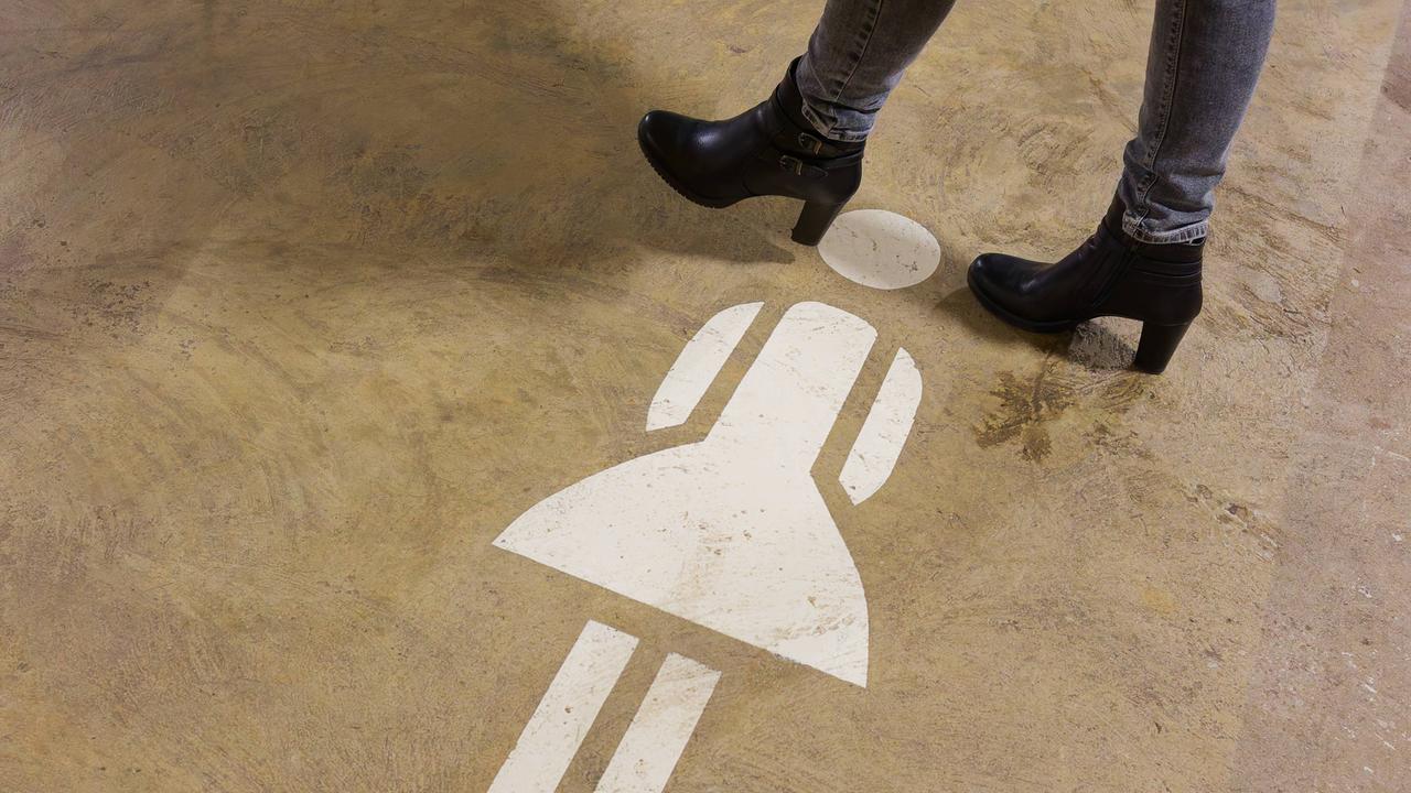 Frauen-Piktogramm auf dem Boden, neben Frauenbeinen