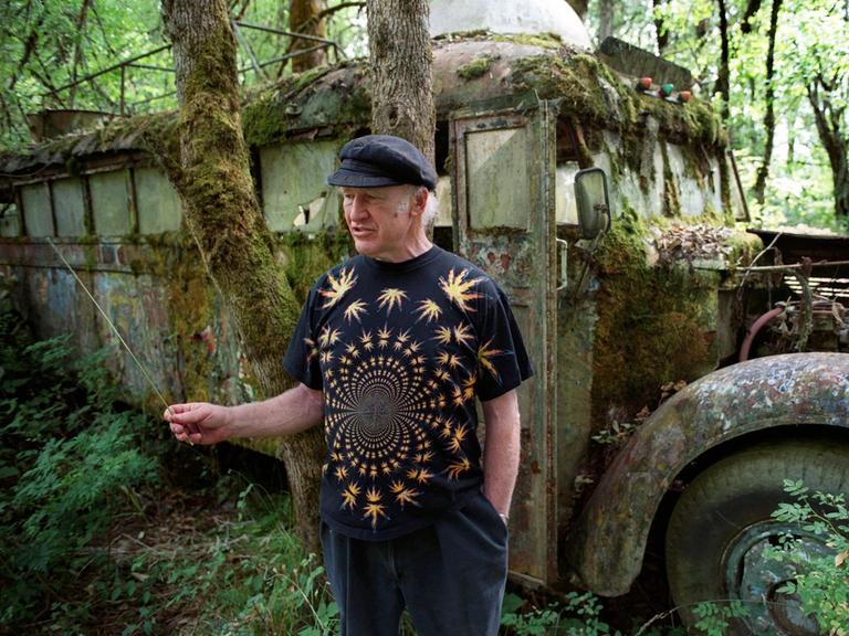 Der amerikanische Schriftsteller Ken Kesey steht im Juli 2001 auf seiner Farm in Pleasant Hill im US-Bundesstaat Oregon vor seinem legendären, ehemals bunt bemalten Bus "Further", der mittlerweile mit Moos bewachsen ist. 