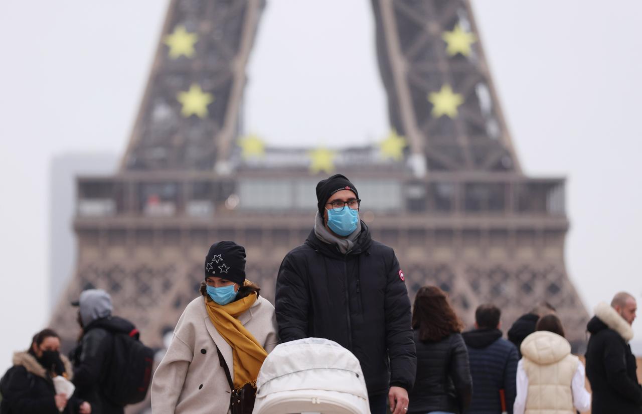 Menschen tragen Schutzmasken und gehen am Trocadero in der Nähe des Eiffelturms in Paris spazieren. 