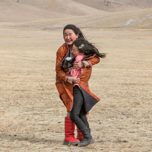 Hatgal, Mongolei, 3. März 2018: Zwei Nomadenmädchen in der Steppe umarmen sich während eines Sandsturms. 