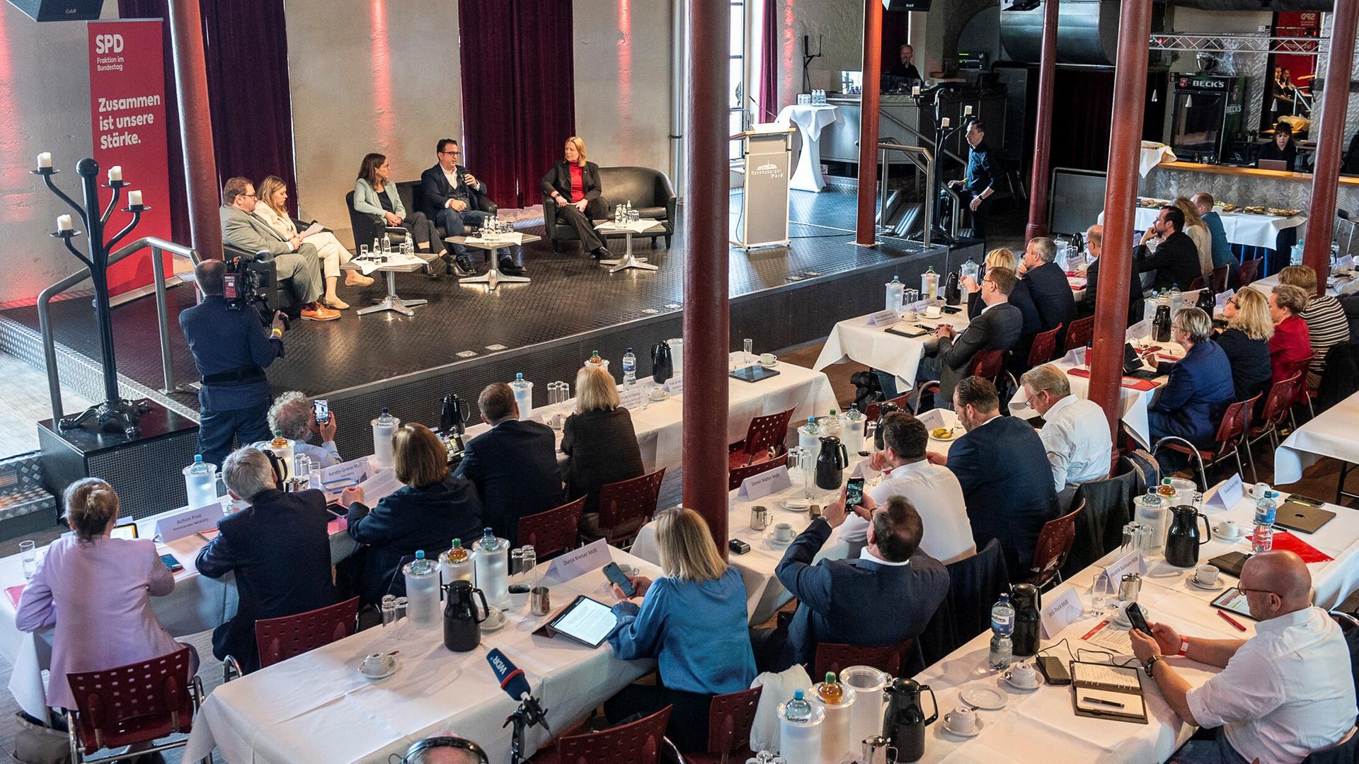Die SPD-Vorsitzende Bärbel Bas (auf dem Podium rechts) spricht zu den Teilnehmern. Blick von einer Empore. 