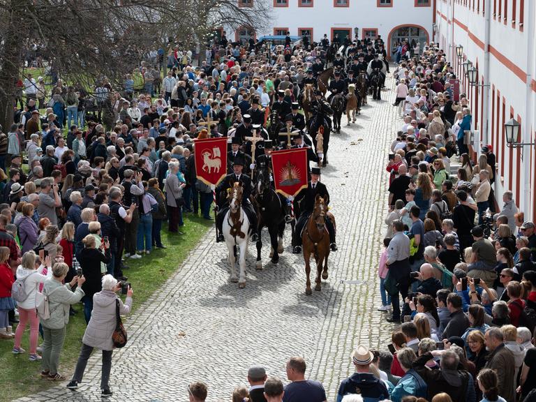Traditionell gekleidete sorbische Osterreiter verkünden nach altem Brauch zu Pferde im Kloster St. Marienstern die Osterbotschaft. Begleitet wird die Prozession von vielen Schaulustigen am Wegesrand.