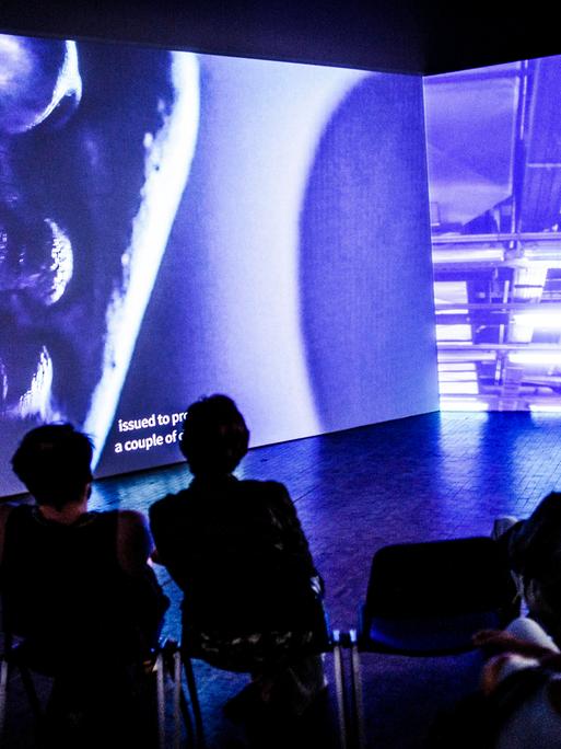 Besucher sitzen vor der Arbeit "again", einer 2 Kanal Installation, des Künstlers Mario Pfeiffer bei der Ausstellung der 10. Berlin Biennale für zeitgenössische Kunst in der Akademie der Künste. 