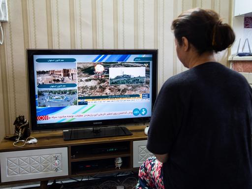 Eine iranische Frau betrachtet die Explosionen der israelischen Angriffe im Fernsehen.