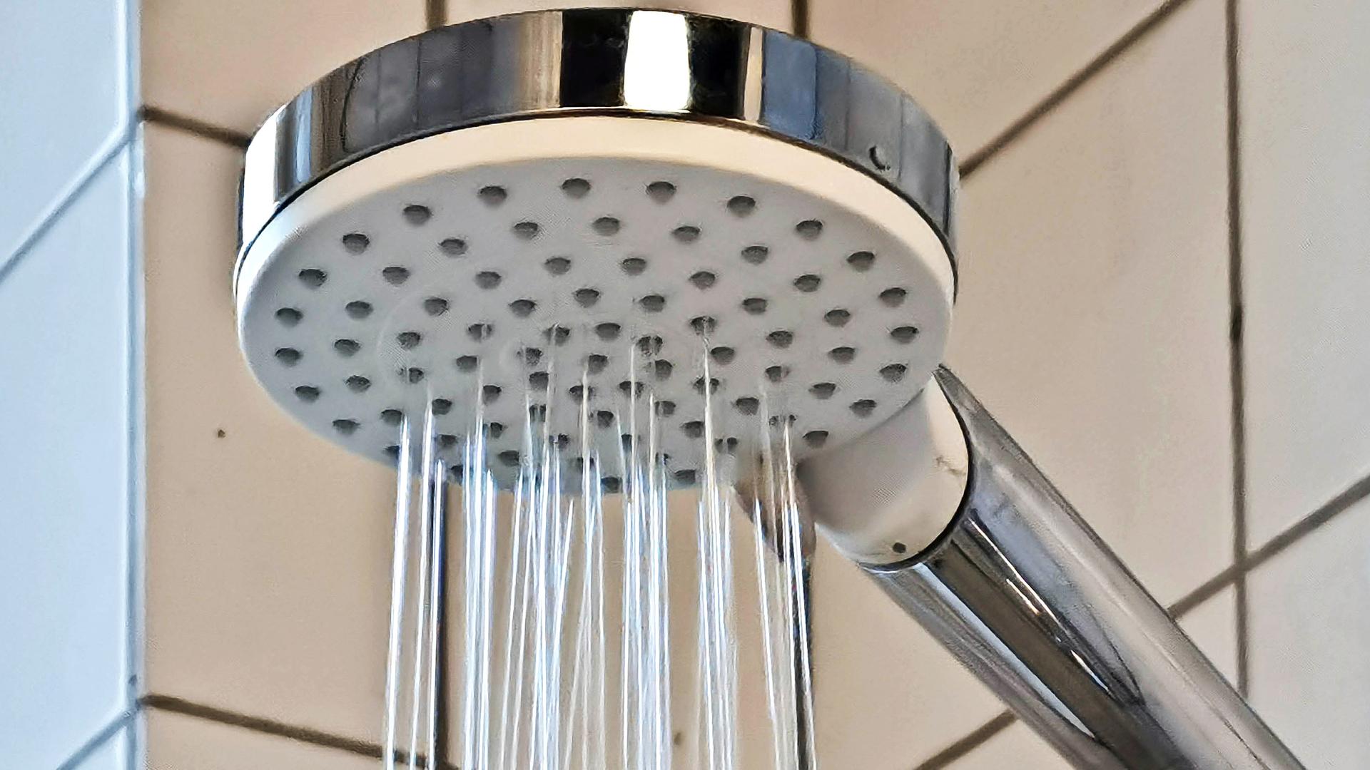 Aus einem wassersparenden Duschkopf läuft Wasser.