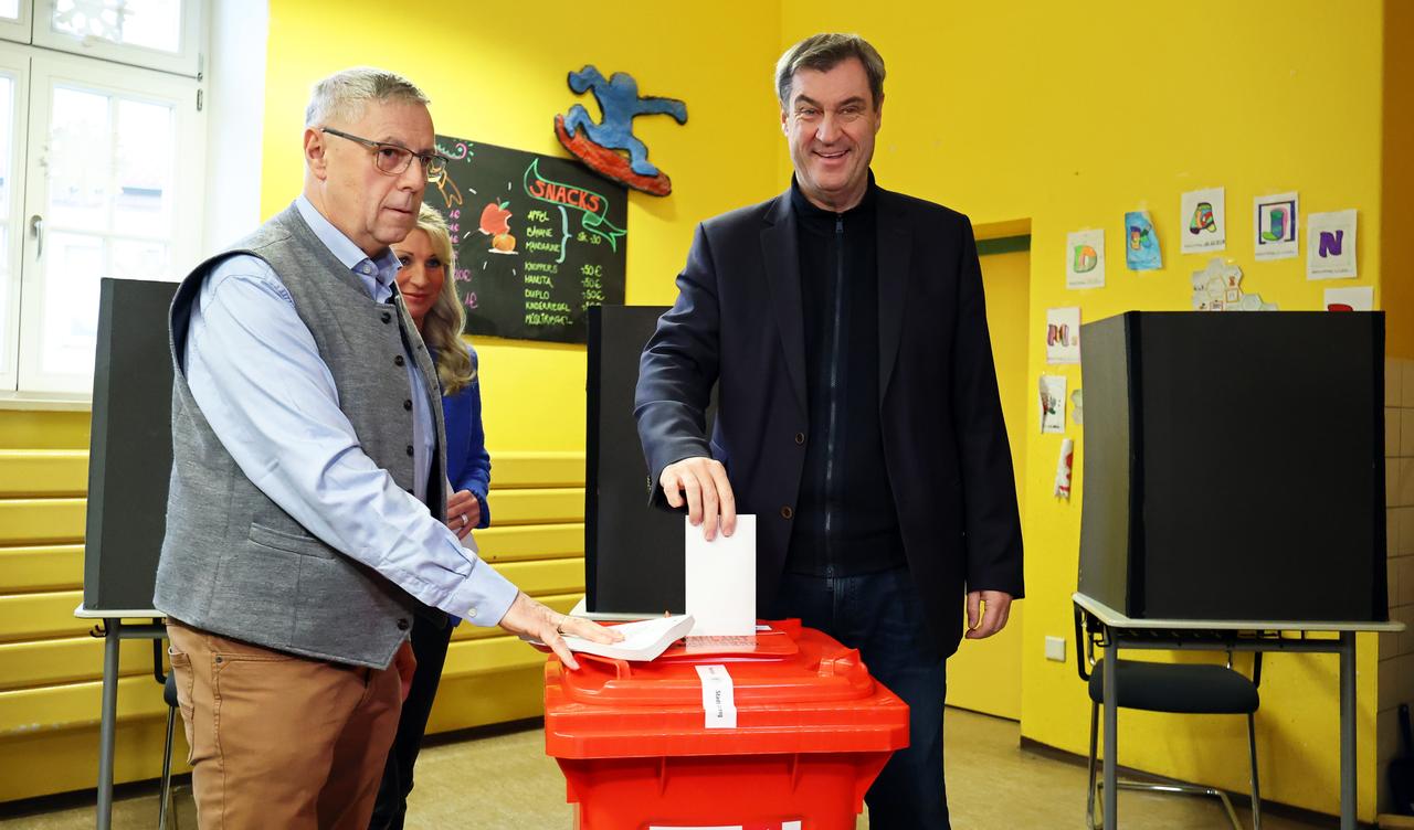 Markus Söder (CSU, r), Ministerpräsident von Bayern, wirft in einem Wahllokal in einer Schule seinen Wahlzettel in die Wahlurne. 