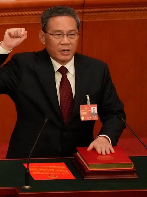 Li Qiang, neu gewählter Ministerpräsident Chinas, reckt eine Faust in die Höhe und legt eine Hand auf die chinesische Verfassung.
