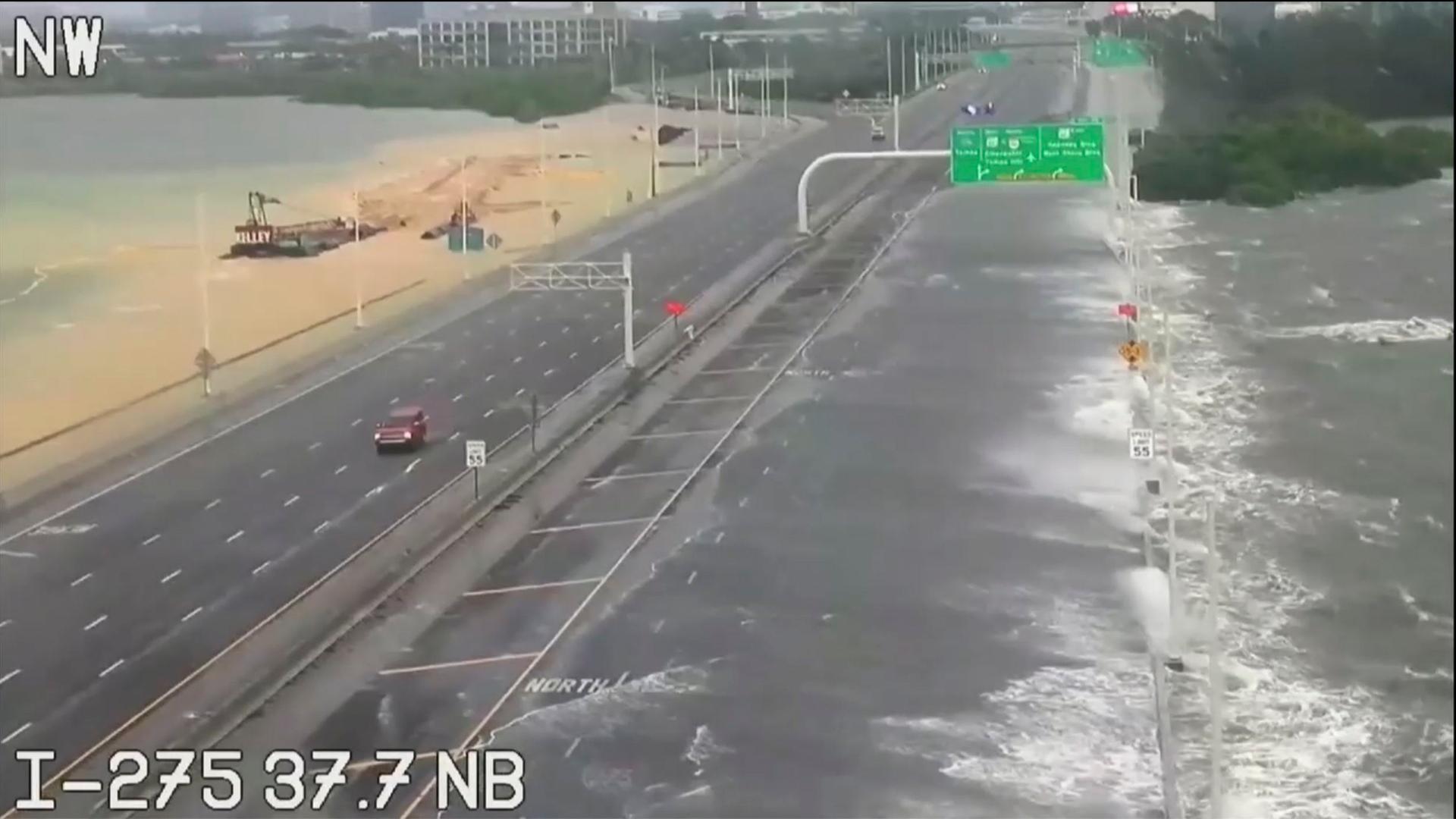 Eine Straße in Tampa Bay in Florida/USA, die fast überschwemmt ist. Starke Wellen kommen am Straßenrand an. Es fährt nur ein Auto. Eine Straße in Tampa Bay in Florida/USA, die fast überschwemmt ist. Starke Wellen kommen am Straßenrand an. Es fährt nur ein Auto.