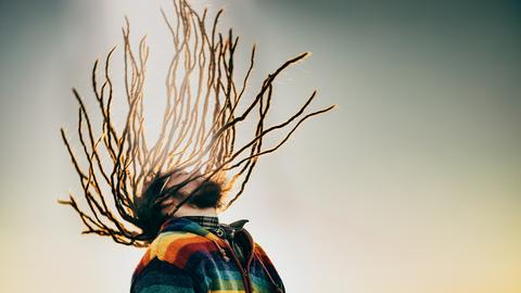 Ein weißer, bärtiger Mann mit schwingender Dreadlock-Frisur.