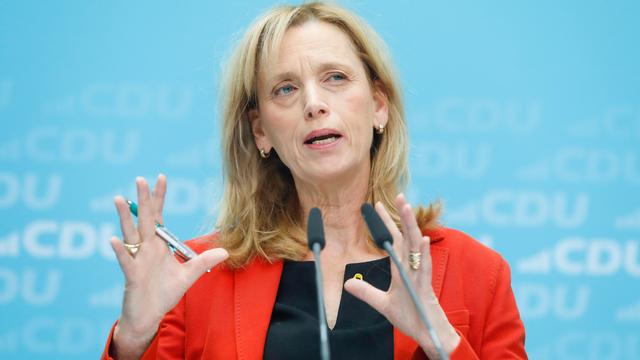 Karin Prien steht vor einem Mikrofon, sie trägt einen roten Blazer.