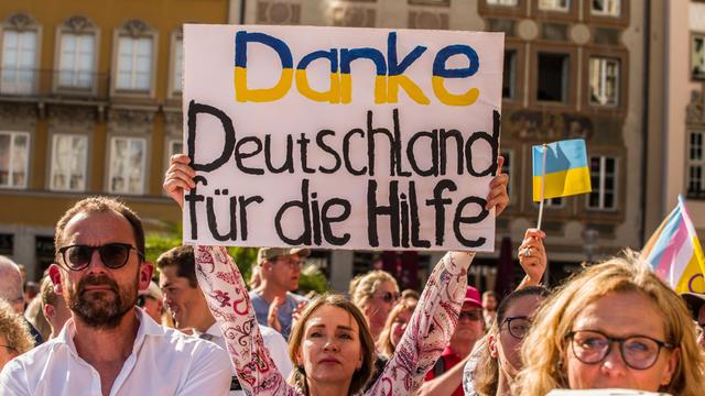 Eine Frau hält auf einer Demo ein Schild hoch mit der Aufschrift: "Danke Deutschland für die Hilfe"