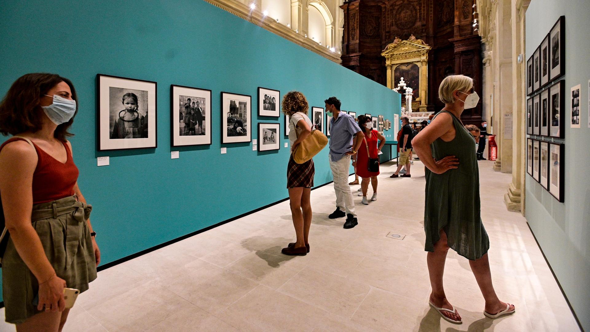 Besucher bei einer Fotoausstellung in Arles betrachten Exponate.