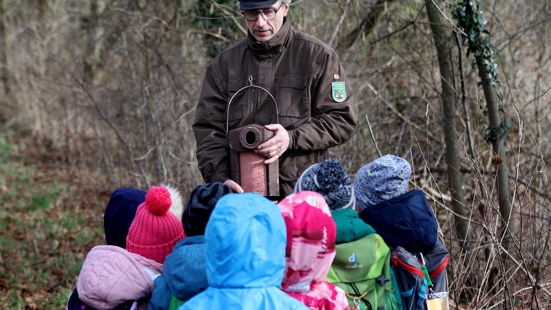 Ein Ranger im Biosphärenreservat Drömling zeigt Kindern einer Kita einen Meisen-Nistkasten. 