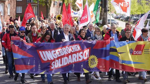 Kundgebung zum Tag der Arbeit am 1. Mai 2023 in Hamburg, Demonstrierende und Vertreterinnen von DGB und IG Metall tragen ein Banner mit dem diesjährigen Motto "Ungebrochen solidarisch".