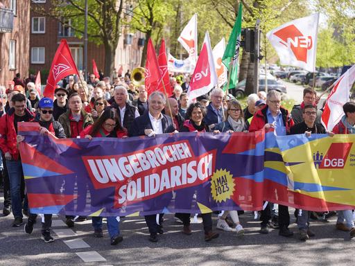 Kundgebung zum Tag der Arbeit am 1. Mai 2023 in Hamburg, Demonstrierende und Vertreterinnen von DGB und IG Metall tragen ein Banner mit dem diesjährigen Motto "Ungebrochen solidarisch".