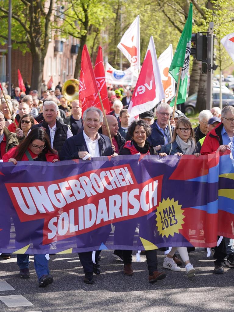 Kundgebung zum Tag der Arbeit am 1. Mai 2023 in Hamburg, Demonstrierende und Vertreterinnen von DGB und IG Metall tragen ein Banner mit dem diesjährigen Motto "Ungebrochen solidarisch".