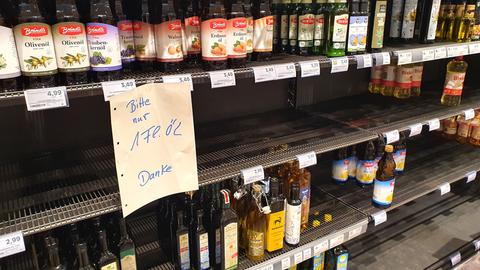 In einem Supermarkt hängt an einem leere Speiseöl-Regal der Hinweis, dass Verbraucher nur jeweils eine Flasche kaufen dürfen. 