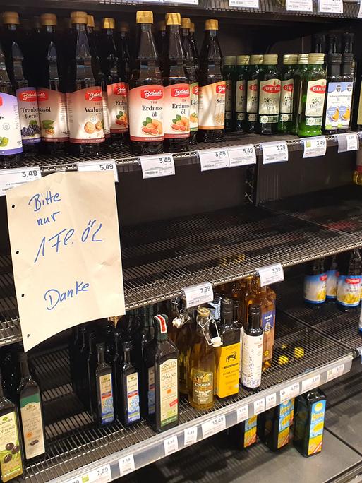 In einem Supermarkt hängt an einem leere Speiseöl-Regal der Hinweis, dass Verbraucher nur jeweils eine Flasche kaufen dürfen. 