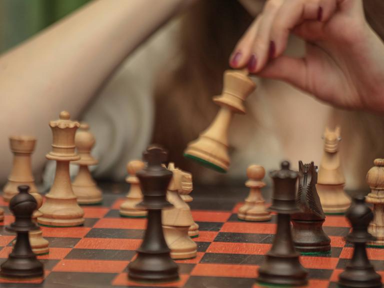 Eine Frau spielt Schach und setzt die Figuren.