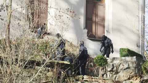 Einsatzkräfte der Polizei stehen auf einem Hang am Jagdschloss Waidmannsheil, während der Durchsuchung durch die Polizei. 