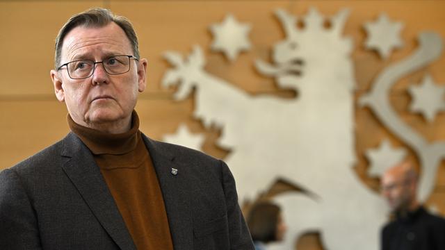 Ramelow im schwarzen Jackett steht vor dem thüringischen Löwen, der hinter ihm an einer Wand im Landtag in Erfurt prangt.