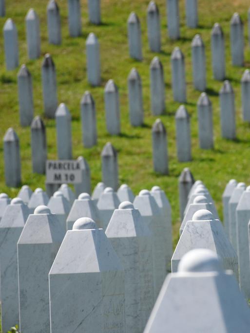 Blick auf die Grabsteine der in Srebrenica getöteten Bosnier auf dem Gedenkfriedhof Potočari: Es sind unzählige weiße Stelen aus Stein.