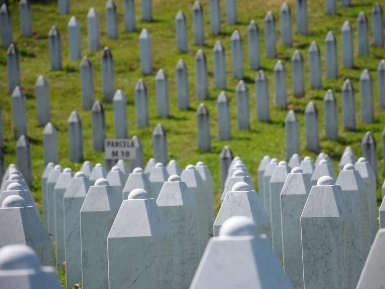 Blick auf die Grabsteine der in Srebrenica getöteten Bosnier auf dem Gedenkfriedhof Potočari: Es sind unzählige weiße Stelen aus Stein.