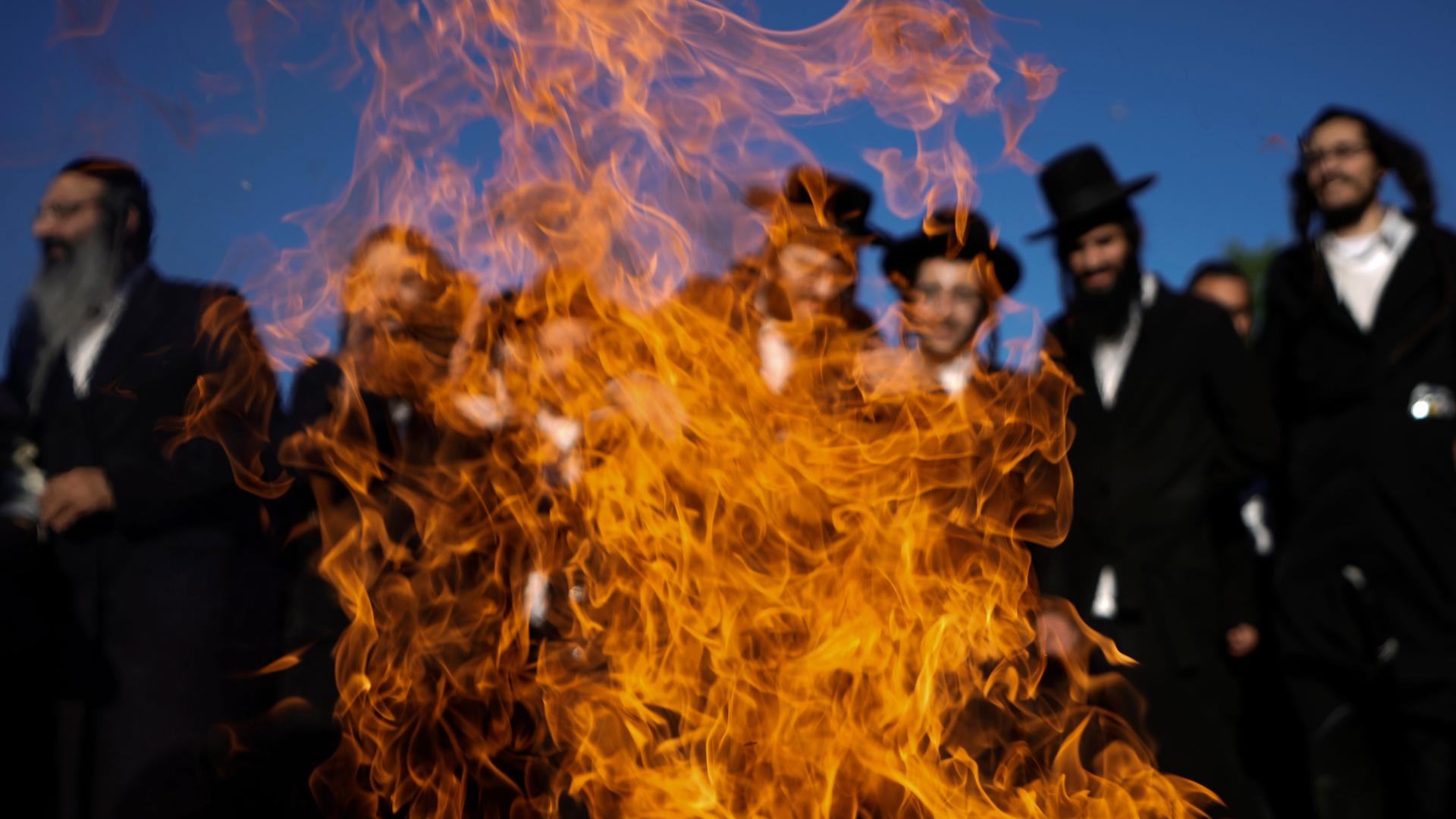 Ultraorthodoxe Juden tanzen bei einer Feierlickeit um ein Feuer herum.