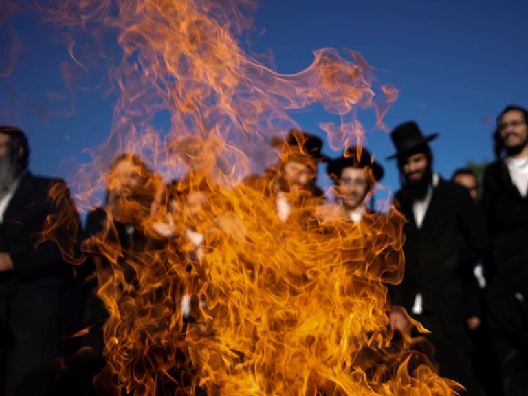 Ultraorthodoxe Juden tanzen bei einer Feierlickeit um ein Feuer herum.