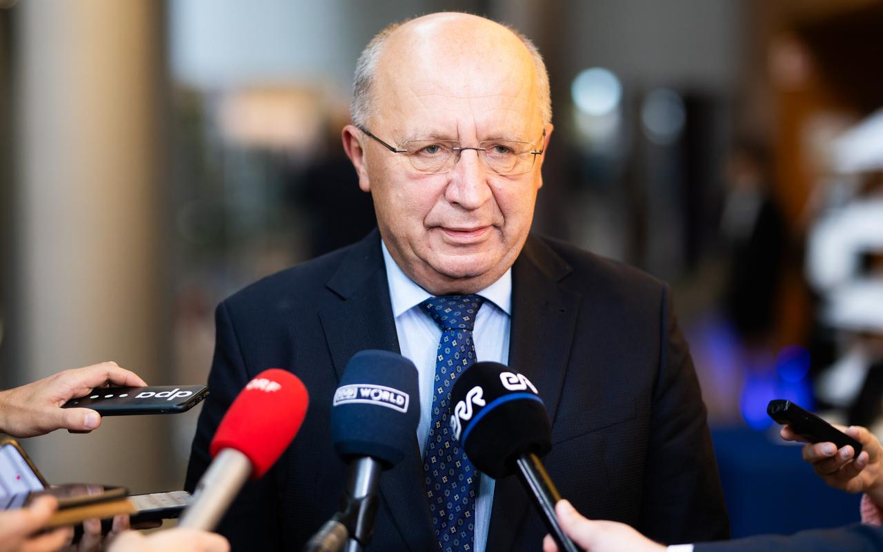 EU-Verteidigungskommissar Andrius Kubilius steht im blauen Anzug mit Hemd und Krawatte vor mehreren Mikrofonen. 